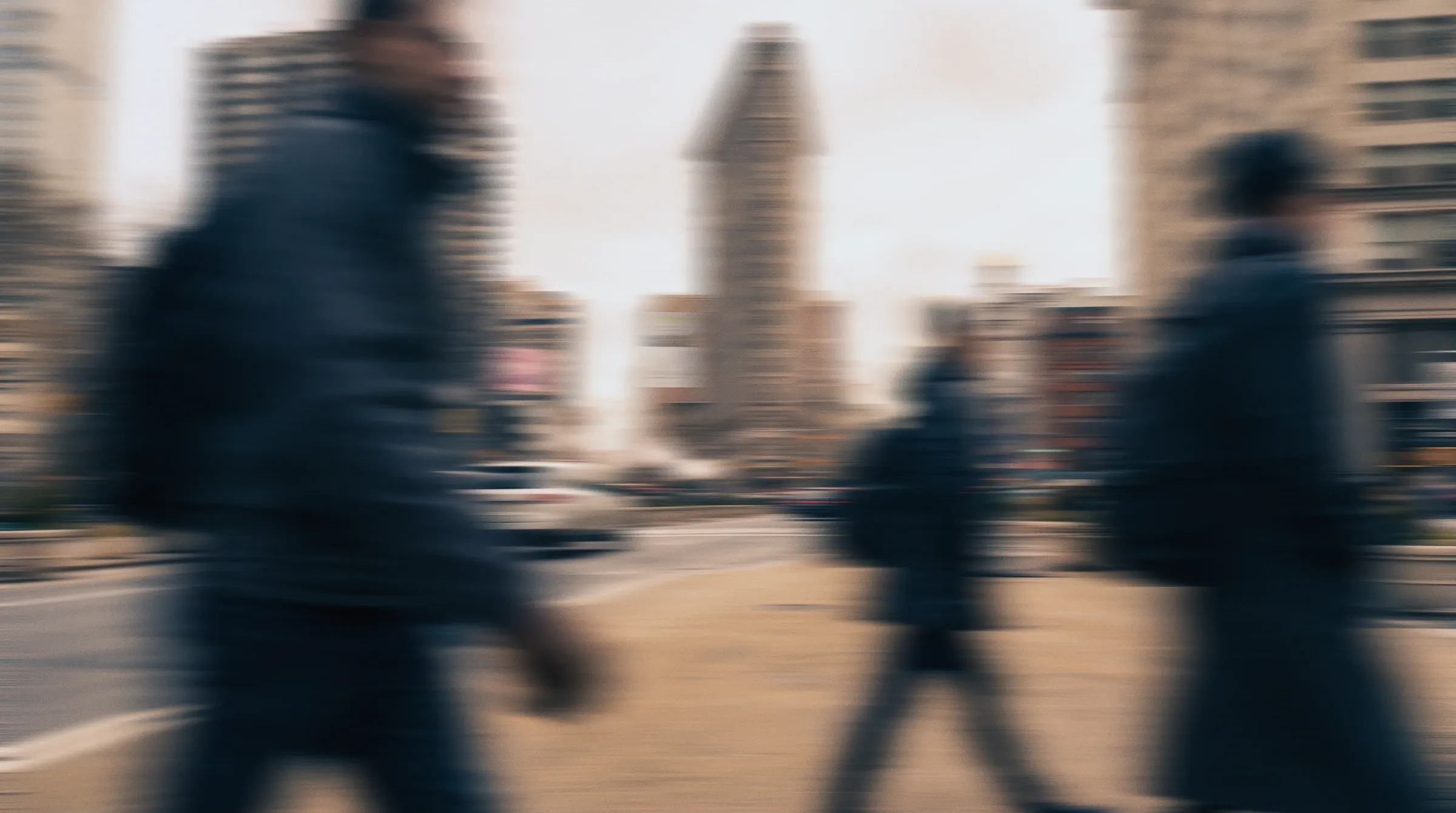 People walking past the Flatiron Building in New York, blurred in motion